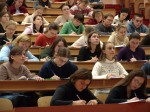 College students in lecture hall taking notes.